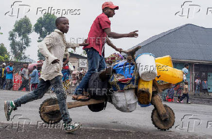 Internally displaced civilians from the camps in Munigi and Kibati, carry their belongings as they flee to Goma