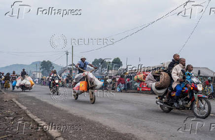 Internally displaced civilians from the camps in Munigi and Kibati, carry their belongings as they flee to Goma