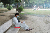 A man uses a face mask to avoid smog, while reading book at a park in Lahore