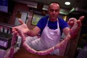 A vendor holds sausages made from pork at a market stall in Rome