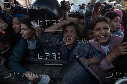 Displaced Palestinians collect donated food in Khan Yunis, southern Gaza