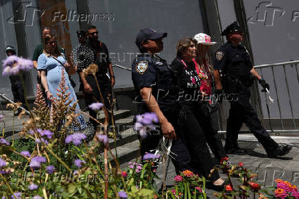 Climate control activists are led away by NYPD in handcuffs after protesting outside the global headquarters of Citigroup as people walk behind in New York City