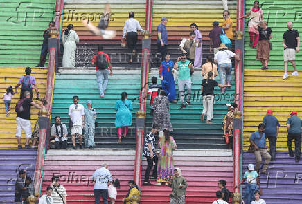Tourists and Hindu devotees are seen on the 272 steps of Sri Subramaniar Swamy Temple at Batu Caves
