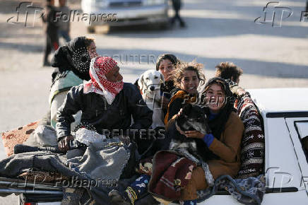 Displaced people who fled from Aleppo countryside, ride on a back of a vehicle with belongings in Tabqa