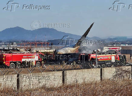 Firefighters carry out extinguishing operations on an aircraft which drove off runway at Muan International Airport in Muan