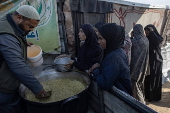 Displaced Palestinians collect donated food in Khan Yunis, southern Gaza