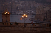 A man looks out over the Grand Harbour at dawn in Valletta