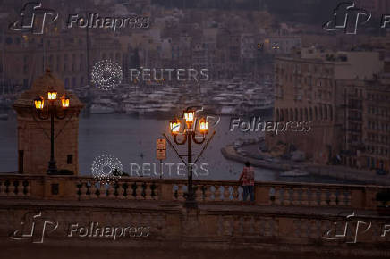 A man looks out over the Grand Harbour at dawn in Valletta