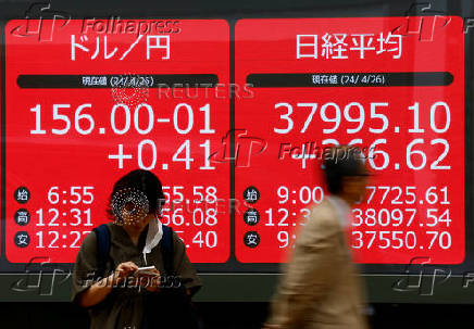 A woman stands in front of an electric screen displaying current Nikkei share average and Japanese Yen exchange rate against the U.S. dollar in Tokyo