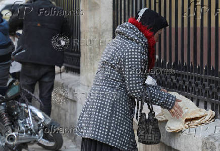 A woman arranges bread along a street in Aleppo