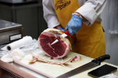 A vendor cuts dry-cured ham at a market stall in Rome