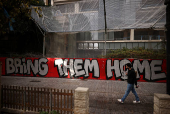 Man walks past graffiti calling for the release of the hostages kidnapped during the deadly October 7 attack by Hamas, in Tel Aviv