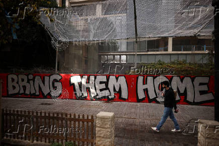 Man walks past graffiti calling for the release of the hostages kidnapped during the deadly October 7 attack by Hamas, in Tel Aviv