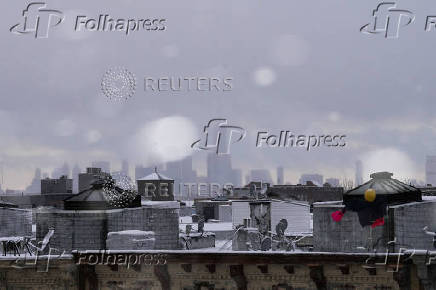 One World Trade Center and the Lower Manhattan skyline is seen during the city's first snowfall of the season, in the Queens borough of New York City