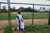 A woman clad in the colours of the Israeli flag waits outside a helipad at the Beilinson Schneider complex, in Petah Tikva