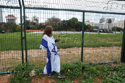 A woman clad in the colours of the Israeli flag waits outside a helipad at the Beilinson Schneider complex, in Petah Tikva