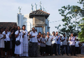 Catholic devotees look at the holy cross while praying at a church during the Holy Friday Passion of the Lord Celebrations in Colombo
