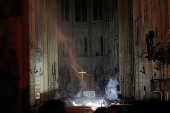 FILE PHOTO: Smoke rises around the altar in front of the cross inside the Notre Dame Cathedral as a fire continues to burn in Paris