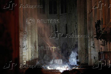 FILE PHOTO: Smoke rises around the altar in front of the cross inside the Notre Dame Cathedral as a fire continues to burn in Paris