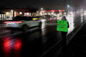 A person holds a sign while standing on the roadside near the McDonald's restaurant where a suspect in the killing of the CEO of UnitedHealthcare, Brian Thompson, was arrested, in Altoona