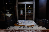 A man sleeps under a blanket outside the entrance to a restaurant during cold temperatures in Washington