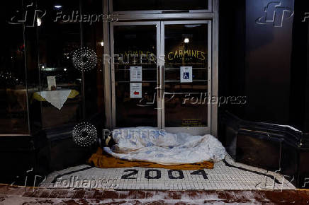 A man sleeps under a blanket outside the entrance to a restaurant during cold temperatures in Washington