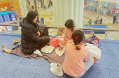 A woman with her daughters eats as they wait for their flight after a rainstorm hits Dubai, causing delays at the Dubai International Airport