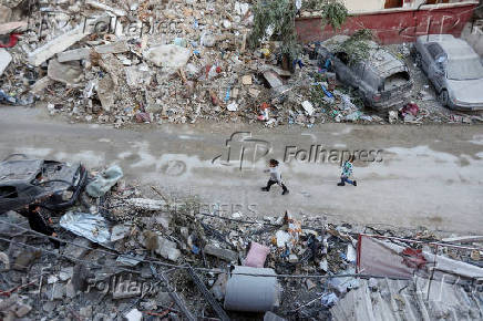 A girl walks along a damaged street, in Tyre