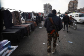 A fighter of the ruling Syrian body walks at a street market in Damascus,