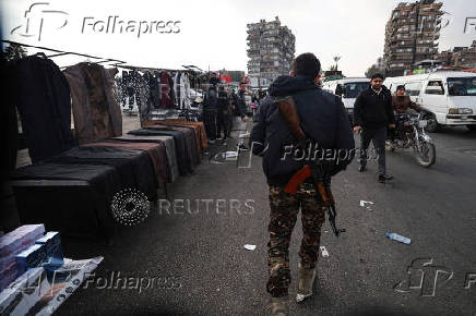 A fighter of the ruling Syrian body walks at a street market in Damascus,