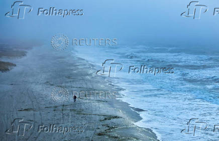 A drone view shows a man and a dog walking along the Atlantic Ocean on Lido Beach in Hempstead, New York