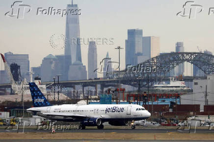 FILE PHOTO: A JetBlue passenger jet lands with New York City as a backdrop