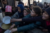 Displaced Palestinians collect donated food in Khan Yunis, southern Gaza