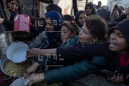 Displaced Palestinians collect donated food in Khan Yunis, southern Gaza