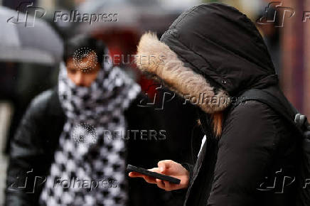 A person wearing a heavy coat looks at a mobile phone