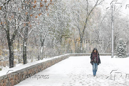 Woman walks along a street during a snowfall in Kyiv