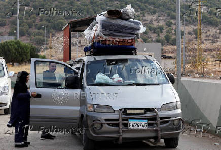 A woman who had fled the hostilities in Lebanon to Syria enters a vehicle as people return to Lebanon through the Masnaa border crossing between the two countries