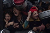 Displaced Palestinians collect donated food in Khan Yunis, southern Gaza