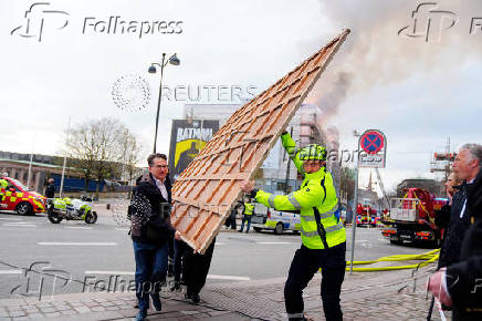 People remove paintings and other objects from the Old Stock Exchange building during a fire, in Copenhagen