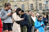 People watch Scottish First Minister Humza Yousaf's resignation announcement on smartphones, outside of Bute House, Edinburgh