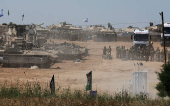 Israeli soldiers gather next to tanks near the Israel-Gaza border, amid the ongoing conflict between Israel and the Palestinian Islamist group Hamas, in southern Israel