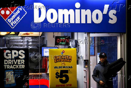 FILE PHOTO: A worker carries a pizza for delivery as he exits a Domino's pizza store in Sydney, Australia