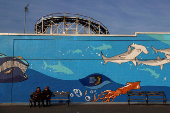 Women sit on the boardwalk of at Coney Island  in the Brooklyn borough of New York City