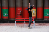 A man stands up from a bench with the posters of Santander Bank in the background, in Malaga
