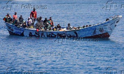 Migrants wait to disembark from a fiber boat in the port of Arguineguin