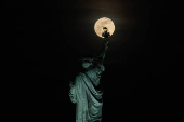 A Lua Rosa (primeira lua cheia da primavera) iluminada em 100 por cento surge atrs da Esttua da Liberdade na cidade de Nova York