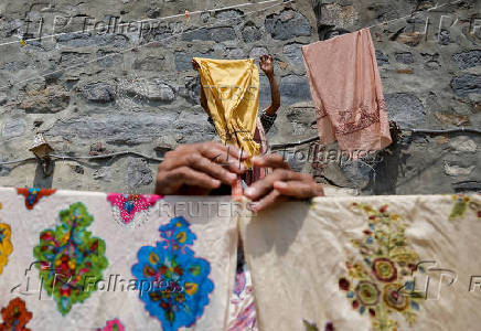 Washermen leave embroidered shawls to dry in the sun, on the banks of river Jhelum, in Srinagar