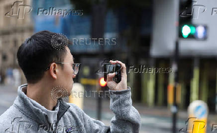 A man takes a photo of the road, using his smartphone in Manchester