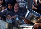 Palestinians gather to receive food cooked by a charity kitchen, amid a hunger crisis, in Khan Younis