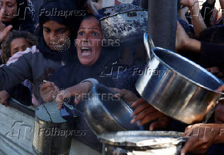 Palestinians gather to receive food cooked by a charity kitchen, amid a hunger crisis, in Khan Younis